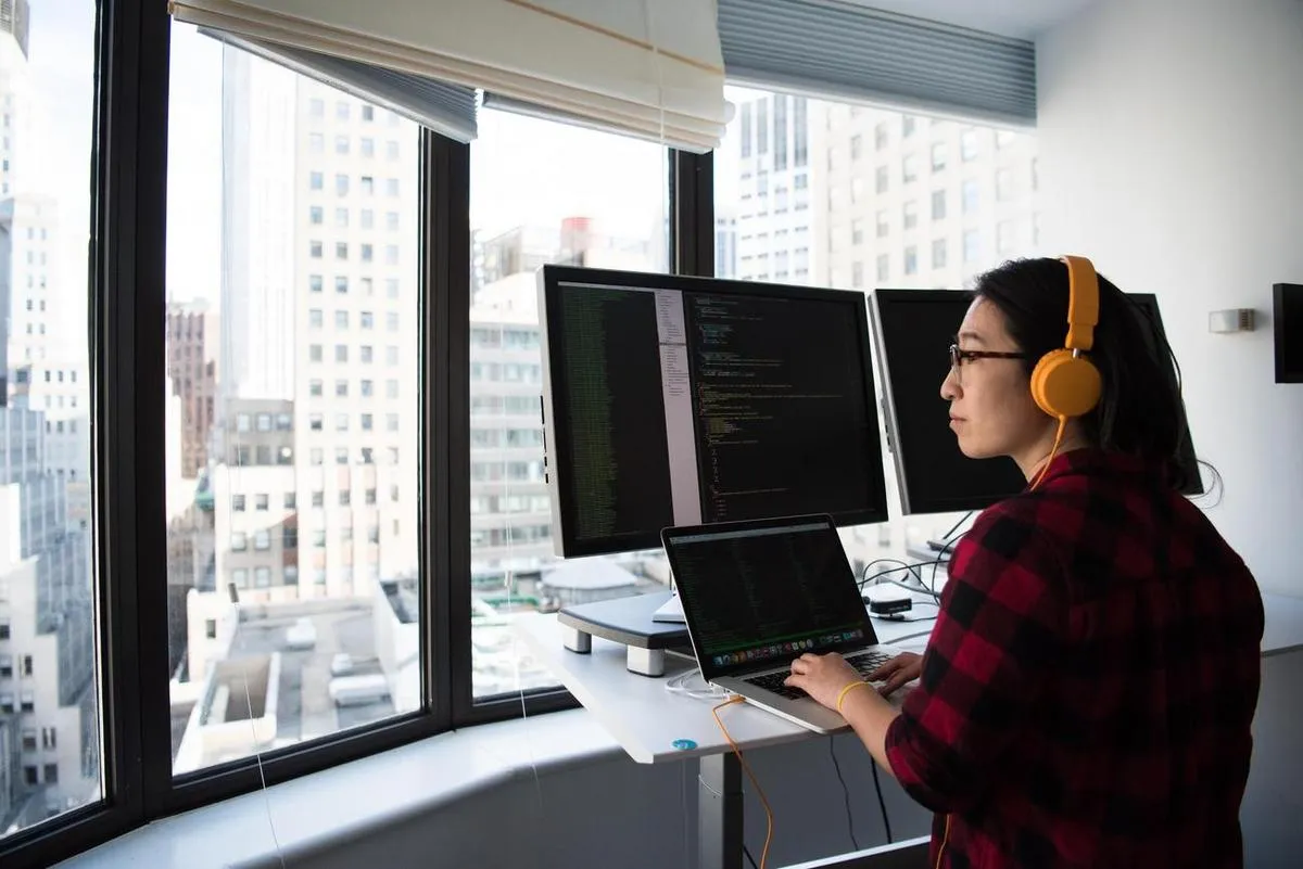 A person at a standing desk in front of monitors setting up a digital sign display.