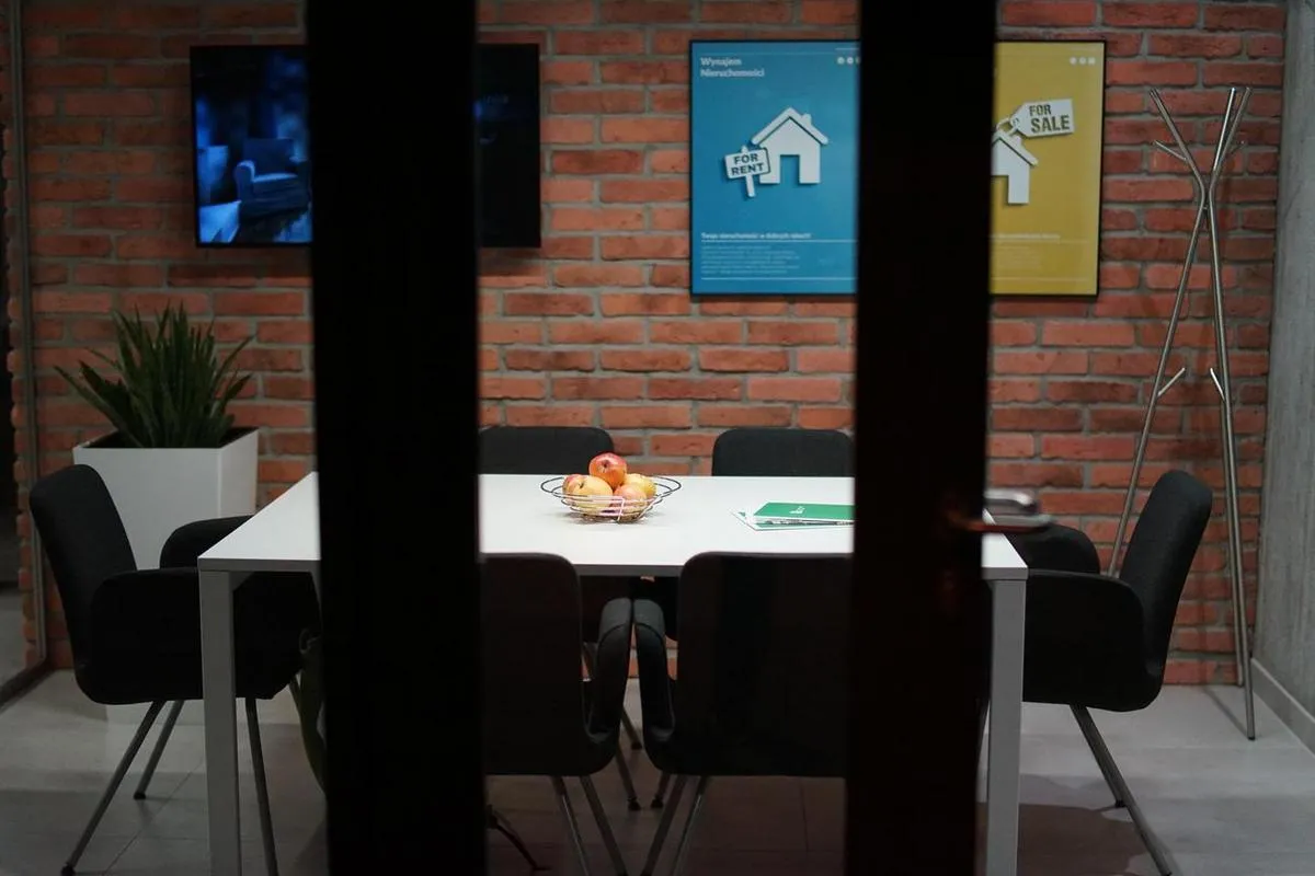 Digital signs in a modern office meeting room against a brick background.