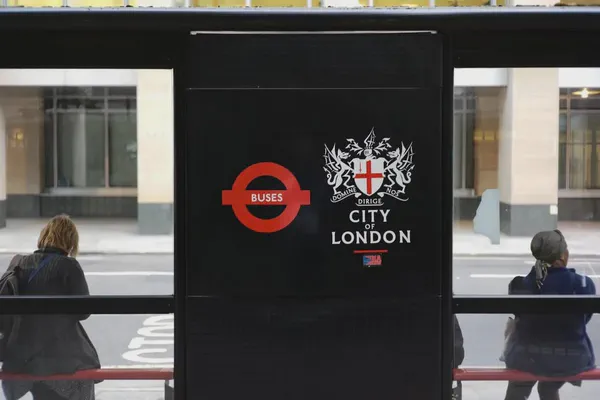 This image is of a digital poster with a black background at a bus stop in London.