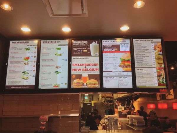A set of digital screens in a fast food restaurant.