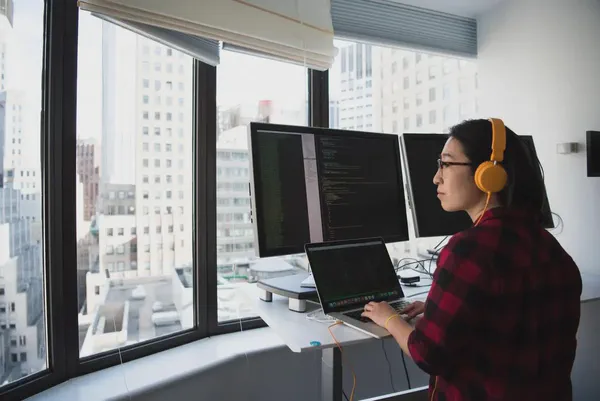 A person at a standing desk in front of monitors setting up a digital sign display.