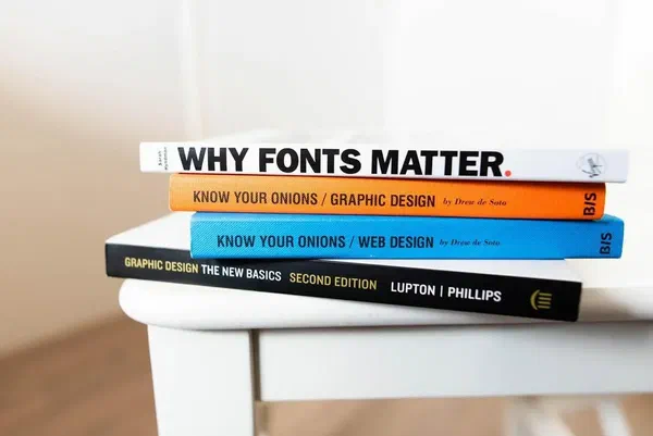 Books on design best practices on top of a white table.