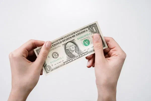 Two hands holding a dollar bill.