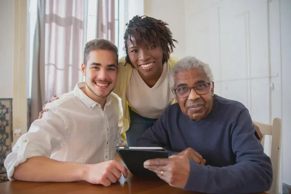 A senior man, a family member, and an assistant at a senior living community.
