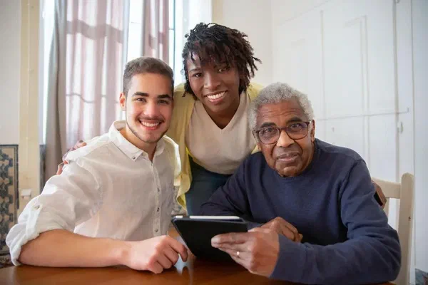 A senior man, a family member, and an assistant at a senior living community.