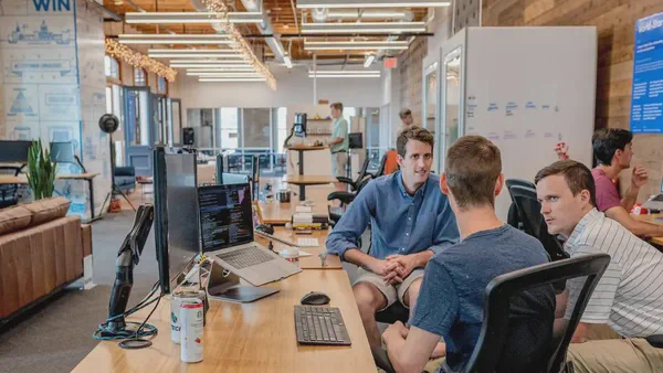 Engaged employees sitting in front of a desk discussing the company's strategy.