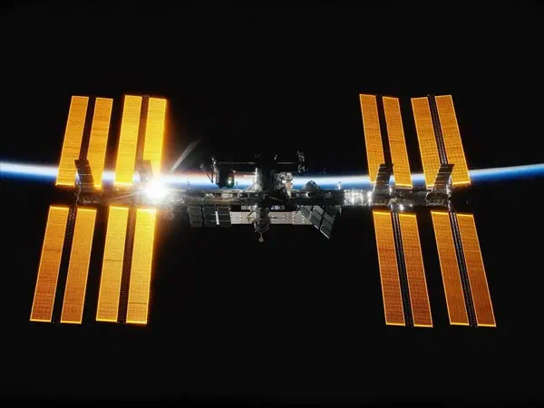 The International Space Station with digital signage inside across the black backdrop of space.