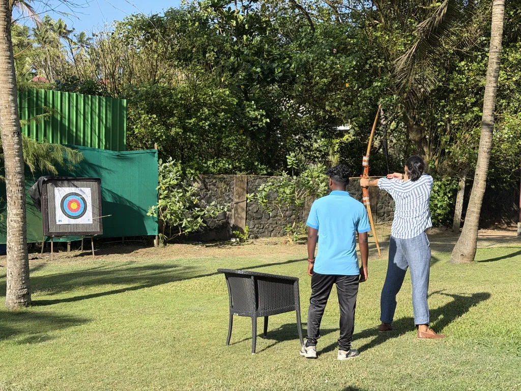 A Screenly team member drawing a bow at the archery range
