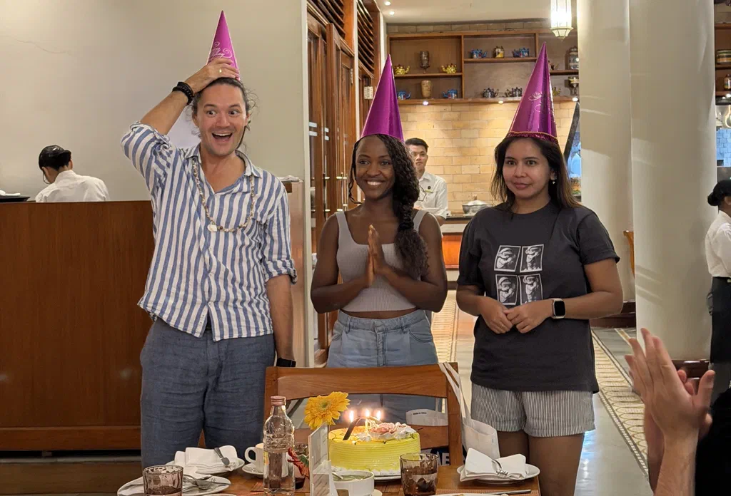 Three Screenly team members in party hats celebrating their birthdays with a cake